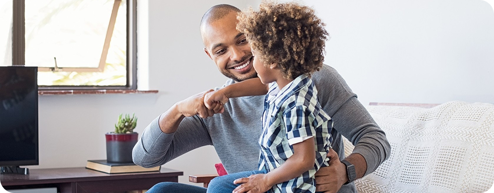 Pai feliz abraçando e dando as mãos ao filho em casa